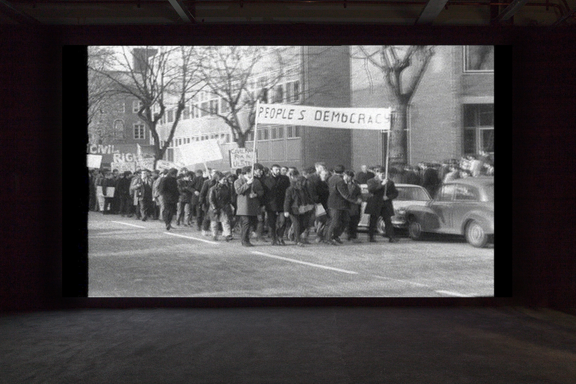Installation view of The Long Note by Helen Cammock, at Void Gallery, film still, marchers for People's Democracy march
