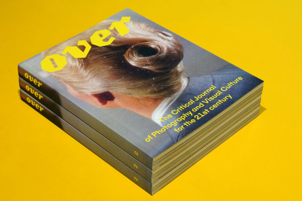 Three stacked magazines showing the cover of OVER Journal on a yellow background.