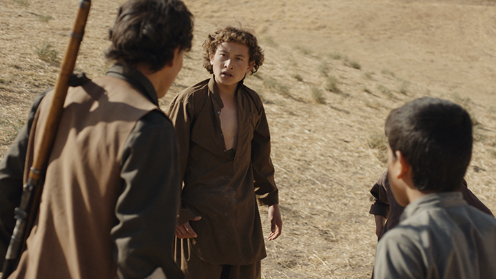 four boys arguing, dressed in brown clothing, on a mountain