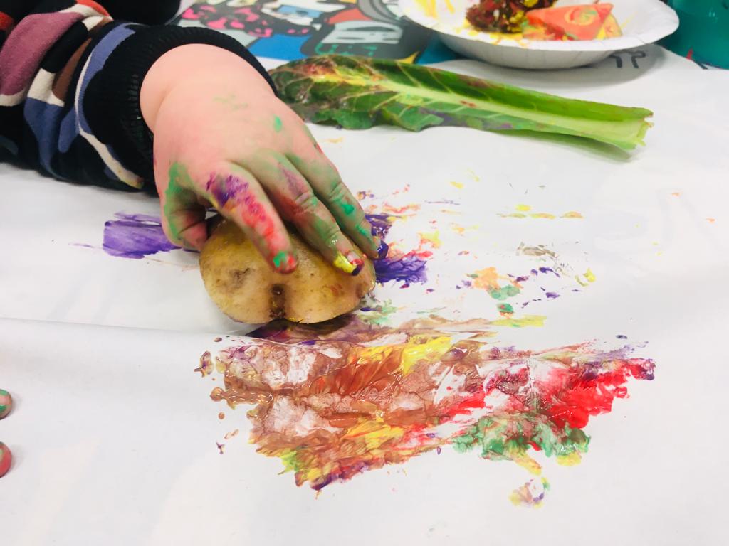 a child's hand soiled with colors holds a sponge on a colored sheet