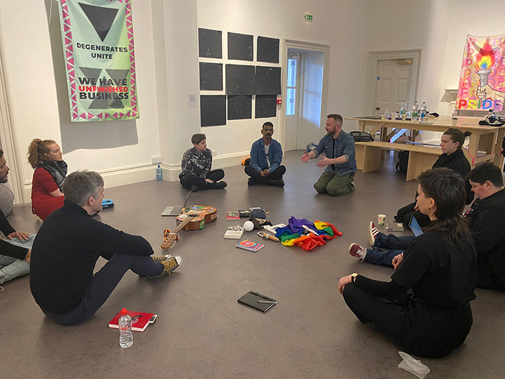 9 people sitting in a circle talking in a room