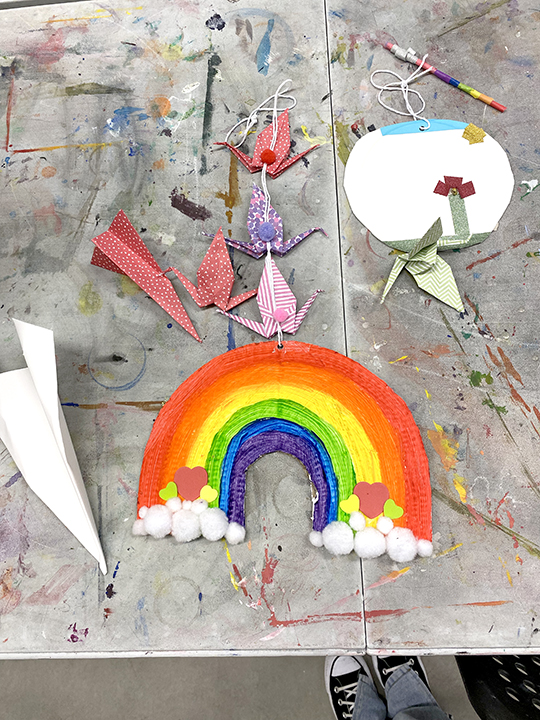 handmade work by a child with a rainbow and card, is on a wooden table