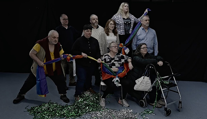9 people posing with a colorful banner