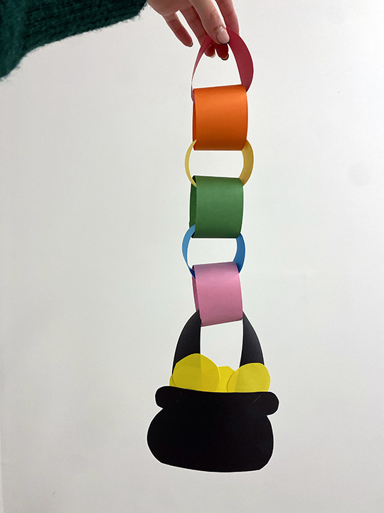 Fabric hoops of various colours are held by a hand from the top of the image