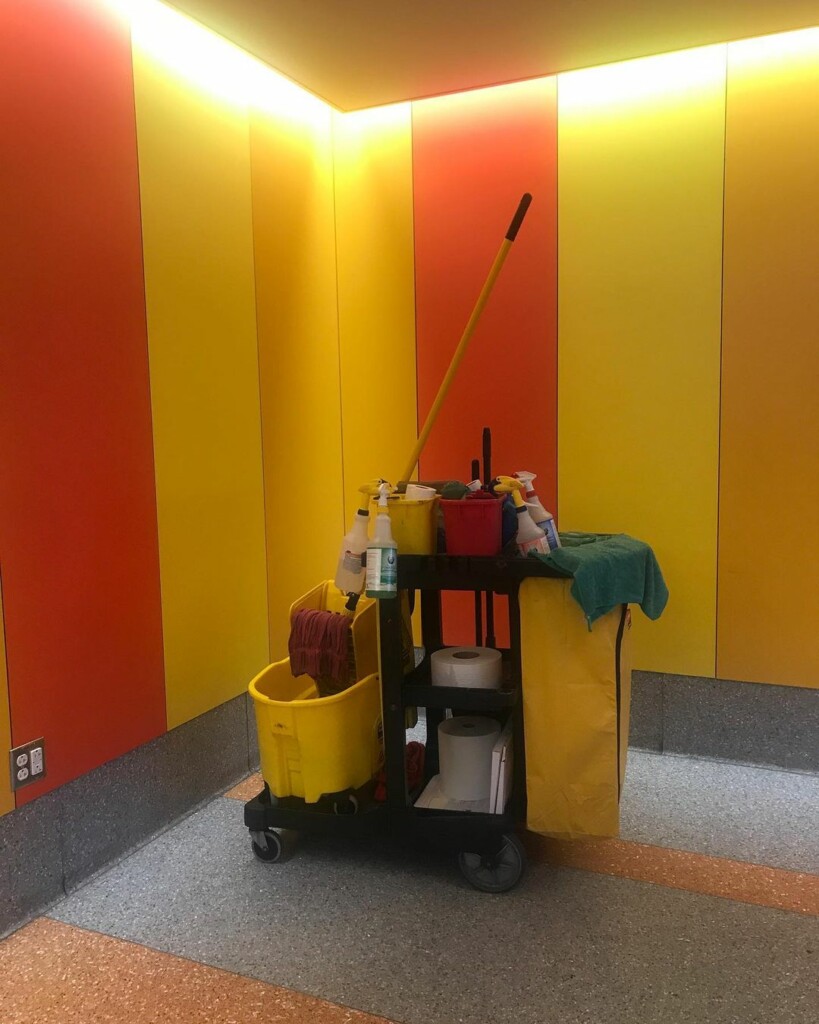 cleaning trolley in a room with red and orange walls, the floor is gray and brown