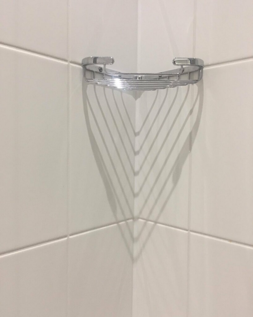 corner between two walls with white tiles. At the top is a soap dish