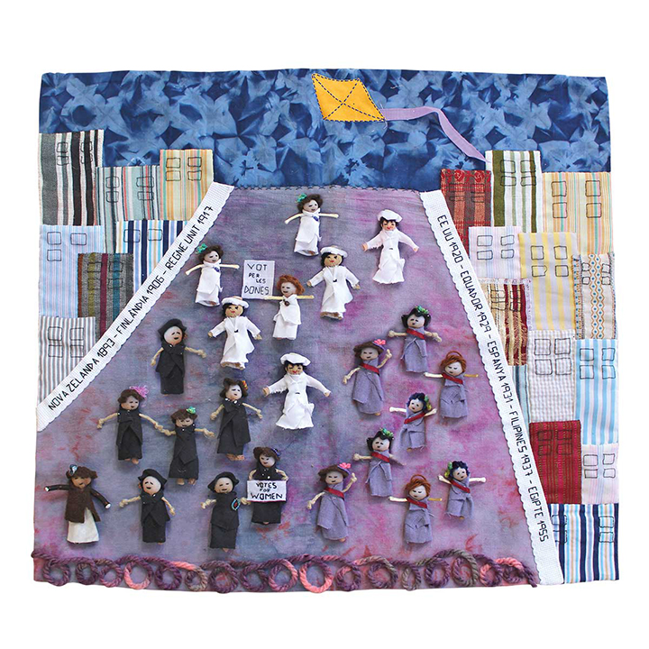 artistic work with puppets in the center on a road that goes from the top to the bottom of the work. On the sides there are buildings made of fabric
