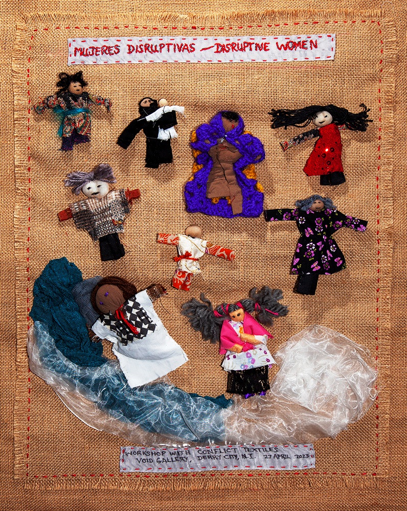 Brown hessian fabric with series of small fabric dolls displayed on it.