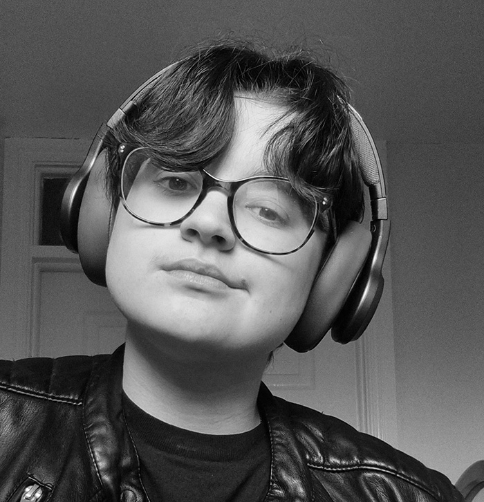 A white person wearing headphones looks into the camera.